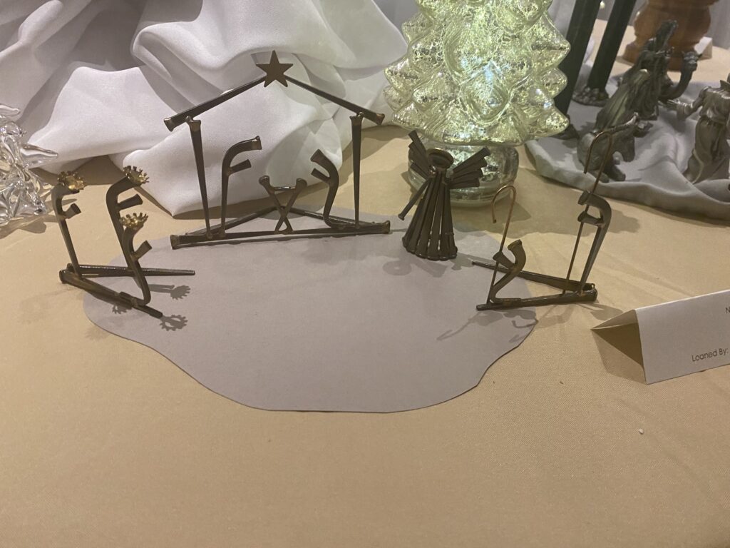 A nativity scene made from metal. Alongside Mary, Joseph, and Baby Jesus, shepards, the three wise men, and an angel are depicted as well.